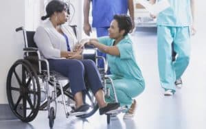 female nurse talking to female patient on wheelchair