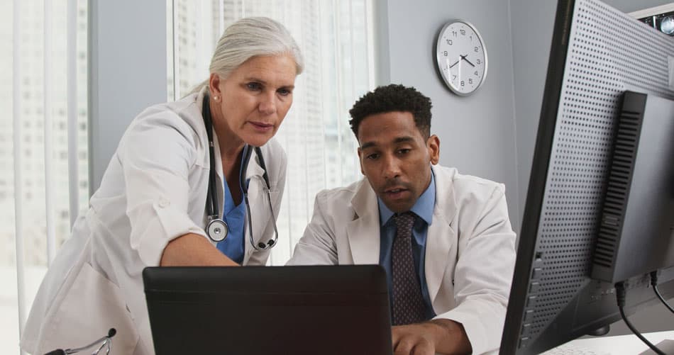 Two physicians working together on laptop - technology concept